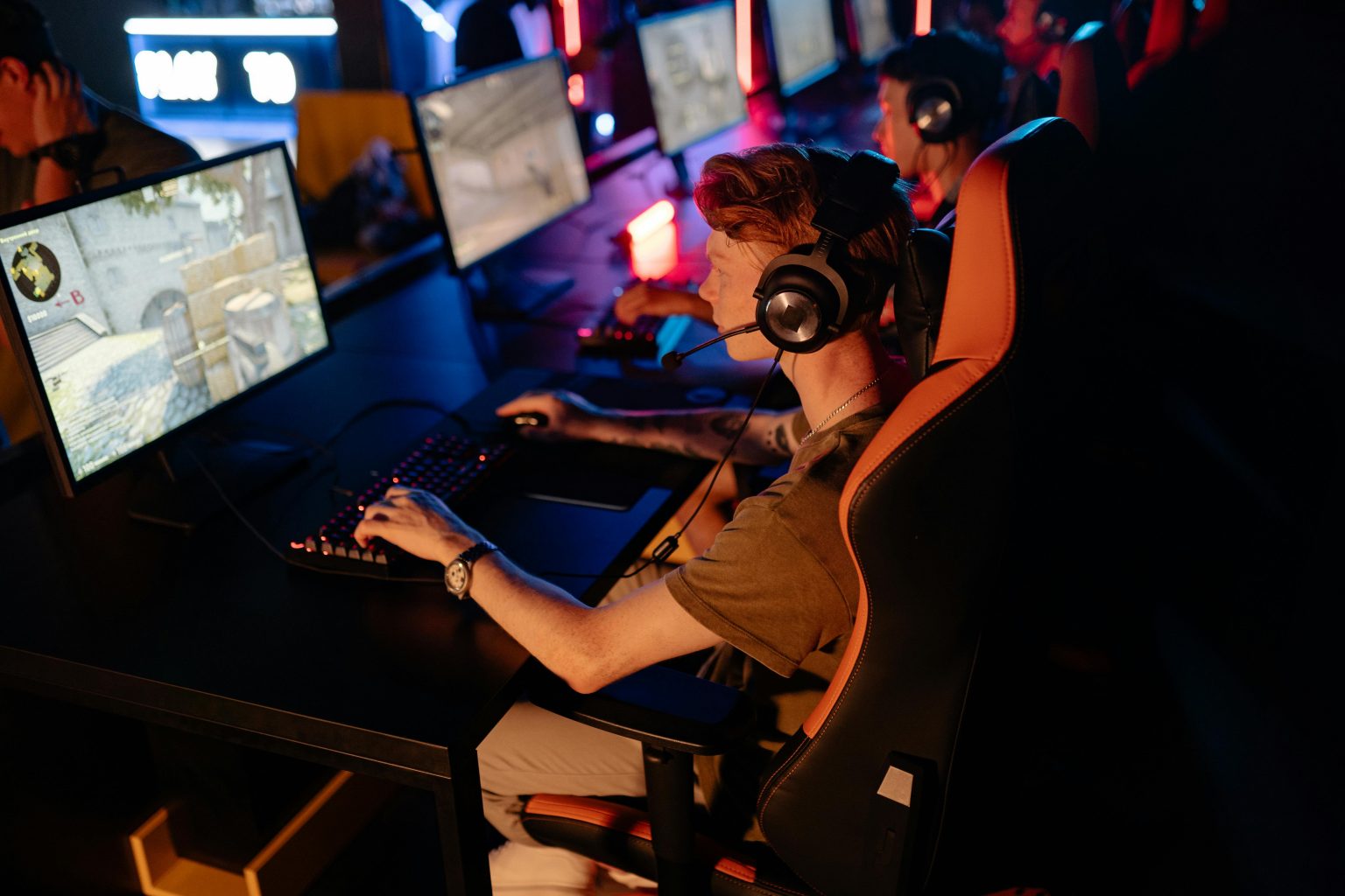 A group of gamers focused on a competitive match in a dimly lit esports arena.